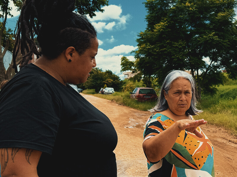 Giorgia Prates conversando com uma moradora ao ar livre