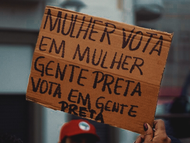 Cartaz com a frase Mulher vota em mulher, gente preta vota em gente preta